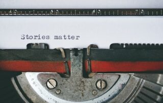 Close up photo of paper and typewriter with the typed phrase Stories Matter, taken by Suzy Hazelwood